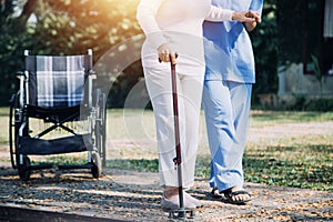 Asian young caregiver nurse support senior older male walking outdoors. Specialist girl doctor help and take care of elderly