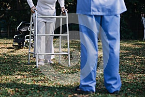 Asian young caregiver nurse support senior older male walking outdoors. Specialist girl doctor help and take care of elderly