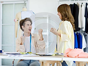 Asian young cheerful excited happy professional male female dressmaker designer seamstress colleague with measuring tape holding