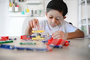 Asian Young Child Concentrate and Focus on Connecting Electronic Constructor. Learning and Experimentation with Circuit Board at