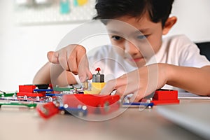 Asian Young Child Concentrate and Focus on Connecting Electronic Constructor. Learning and Experimentation with Circuit Board at