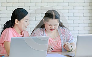 Asian young chubby down syndrome autistic daughter learning mathematic lesson from happy mother via laptop computer at home.