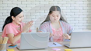 Asian young chubby down syndrome autistic daughter learning mathematic lesson from happy mother via laptop computer at home.