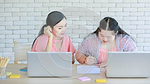 Asian young chubby down syndrome autistic daughter learning mathematic lesson from happy mother via laptop computer at home.