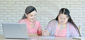 Asian young chubby down syndrome autistic daughter learning mathematic lesson from happy mother via laptop computer at home.