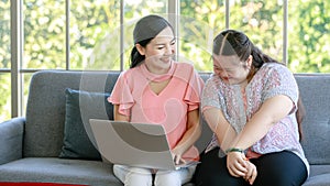 Asian young chubby down syndrome autistic daughter learning mathematic lesson from happy mother via laptop computer at home.