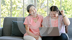 Asian young chubby down syndrome autistic daughter learning mathematic lesson from happy mother via laptop computer at home.