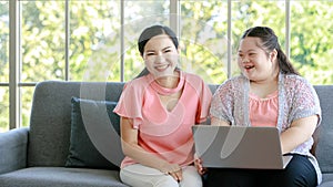 Asian young chubby down syndrome autistic daughter learning mathematic lesson from happy mother via laptop computer at home.