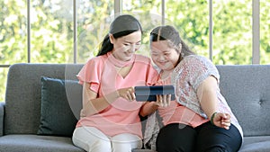 Asian young chubby down syndrome autistic daughter learning mathematic lesson from happy mother via laptop computer at home.