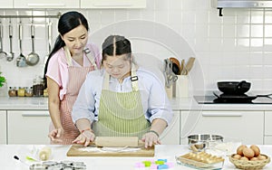 Asian young chubby down syndrome autistic daughter wears apron hugging cuddling showing love to mother sitting cutting sweet