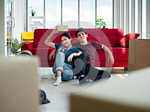 Asian young couple boy and girl relaxed sitting after break from carrying and opening cardboard and parcel box in new home
