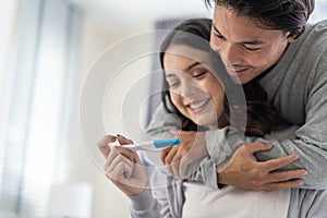 Asian young couple feeling happy after look at positive pregnancy test. Beautiful loving woman surprises boyfriend with good news