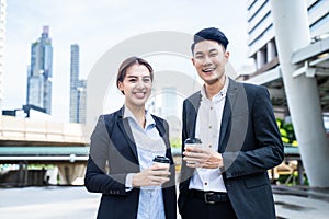 Asian young couple office business people stand outdoor in city with confident face holding hot coffee. Working man and woman feel