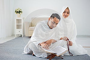 Asian young couple praying with Al-Qur`an and prayer beads