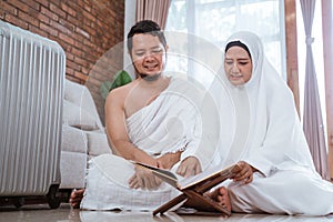 Asian young couple praying with Al-Qur`an and prayer beads