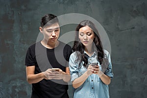 Asian young couple using cellphone, closeup portrait.