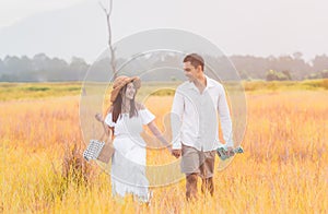 Asian young couple walking and holding hands in meadow