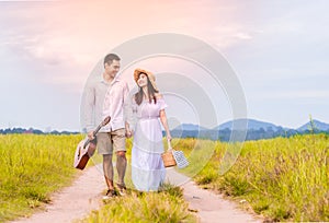 Asian young couple walking and holding hands in meadow with happiness