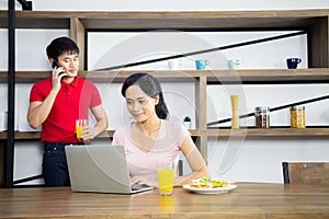 Asian Young couple,Woman are looking business in laptop and behind have a man talking mobile phone