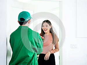 Asian young customer girl surprise and impress when delivery man send pink rose bouquet after knock the door