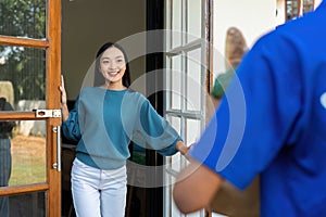 Asian young delivery man delivering package to female customer at home