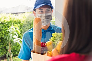Delivery man wear protective face mask making grocery giving fresh food to woman customer