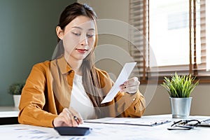 Asian young employee, business woman calculate tax income and expenses, bills, credit card for payment or payday on table at home