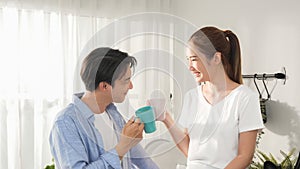 Asian young family couple boy and girl smile with cheers a mug of coffee and hot chocolate milk before drink and sitting on