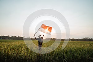 Asian young father with doughter flapping Indonesian flag