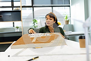 Asian young female architect analyzing architectural model in office
