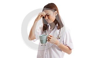 Asian young female doctor got headache with a cup of coffee.