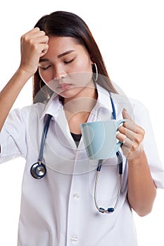 Asian young female doctor got headache with a cup of coffee.