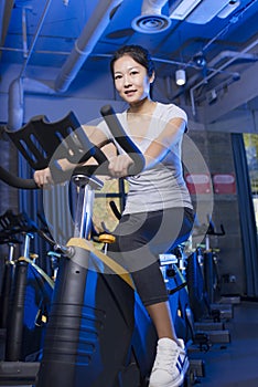 Asian young female exercising on gym bike