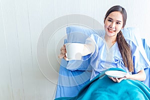 Asian young female patients are drinking warm water on a patient bed in the recovery room. And bright facial expressions in the