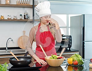 Asian young frowning face female housewife chef wearing white tall cook hat and apron standing holding hand closing nose mixing