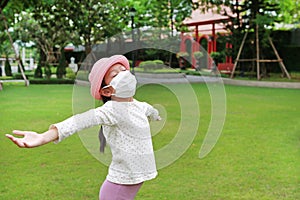 Asian young girl child wearing medical mask with open wide arms due covid-19 on the garden