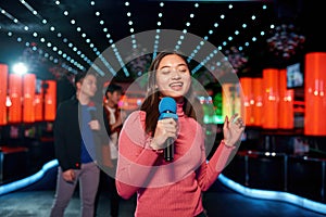 Asian young girl with friends dancing and singing at karaoke bar