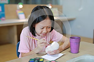 Asian young girl painting a doll with watercolor. Kid with water color painting activity