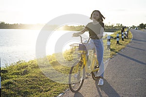 Asian young girl sitting on yellow bicycle on the road nearly river