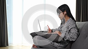 Asian young girl using laptop computer studying homework during her online lesson.