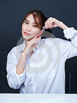 Asian young glamour trendy urban fashionable female model wearing makeup in casual white shirt sitting smiling holding red lipstic