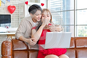 Asian young handsome male boyfriend standing smiling behind giving red wrapped present gift box beautiful female girlfriend