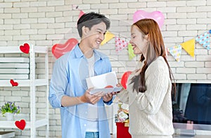 Asian young handsome male boyfriend standing smiling playing cuddling with beautiful female girlfriend holding red heart shape