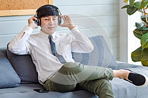 Asian young handsome professional successful male businessman employee in formal business shirt and necktie sitting on cozy sofa