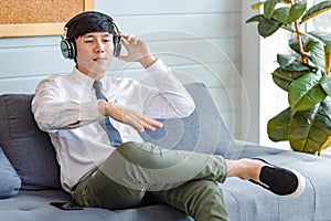 Asian young handsome professional successful male businessman employee in formal business shirt and necktie sitting on cozy sofa