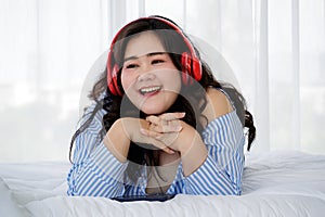 Asian young happy calm fat overweight woman lay down with happy smiling deep emotion peacefully while listening to music from big