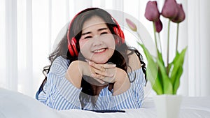 Asian young happy calm fat overweight woman lay down with happy smiling deep emotion peacefully while listening to music from big