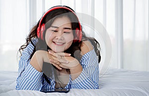 Asian young happy calm fat overweight woman lay down with happy smiling deep emotion peacefully while listening to music from big