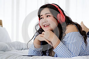 Asian young happy calm fat overweight woman lay down with happy smiling deep emotion peacefully while listening to music from big