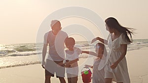 Asian young happy family enjoy vacation on beach in evening. Dad, mom and kid relax walking together near sea when sunset.